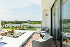Un balcón moderno con piscina, mobiliario exterior y vistas a una zona residencial.