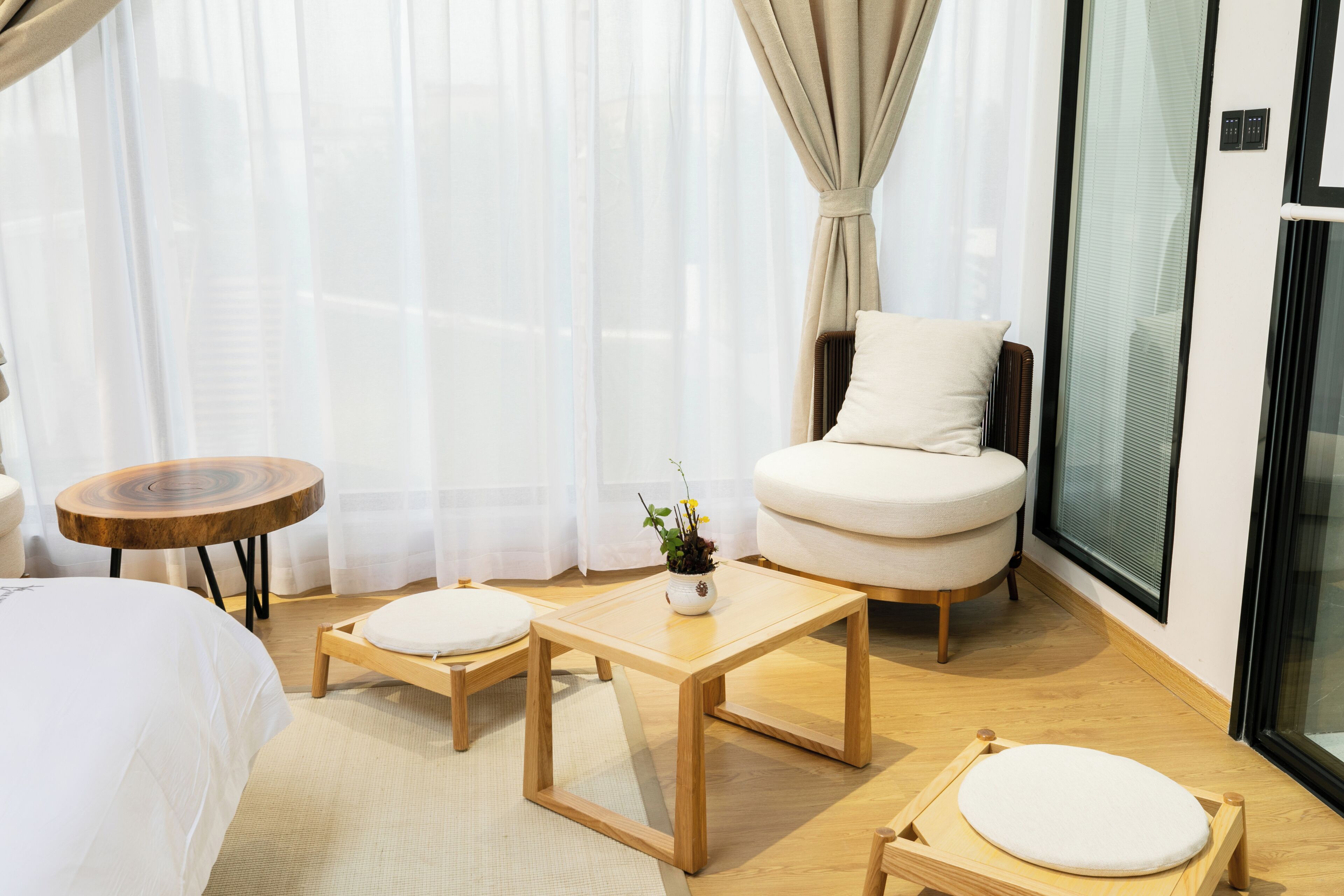 Una habitación de hotel moderna con una cama, un sillón redondo, una mesita y una planta en maceta.