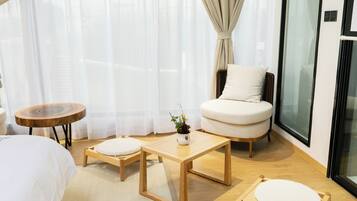 Una habitación de hotel moderna con una cama, un sillón redondo, una mesita y una planta en maceta.