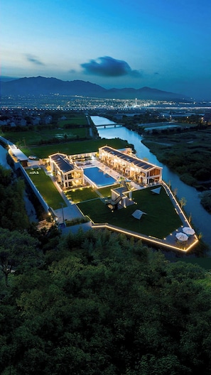 A large, modern hotel complex with multiple buildings, a swimming pool, and a river running through the property. - Shanghai Fangwai Resort & Homestay (Shanghai)