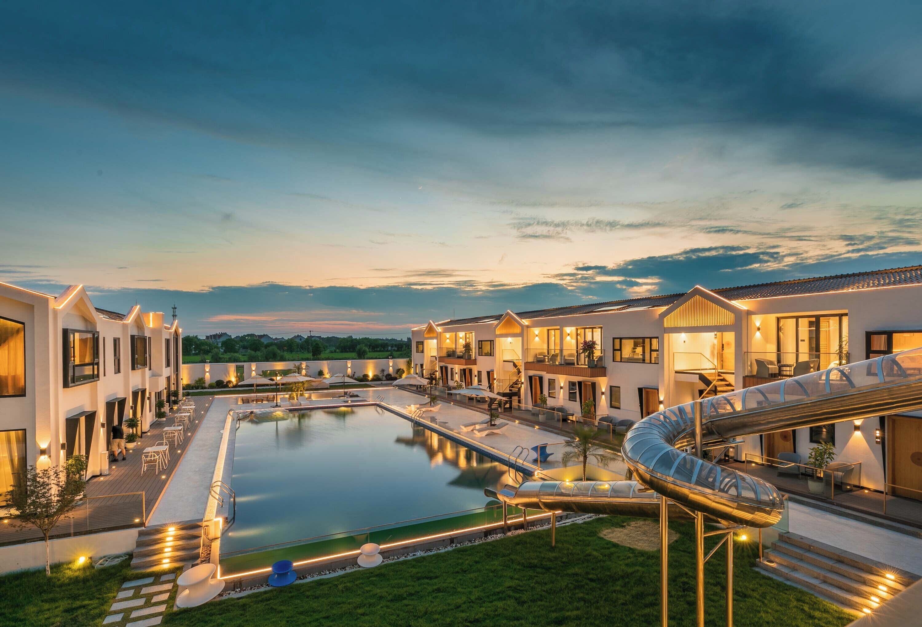 Un hotel moderno con piscina, zona de estar exterior y tobogán de agua.