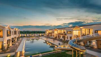 Un hotel moderno con piscina, zona de estar exterior y tobogán de agua.