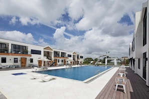 Una piscina al aire libre, sombrillas, tumbonas