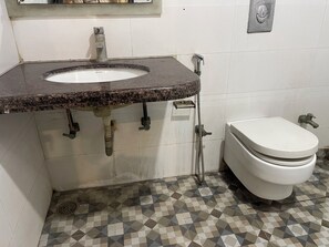Un baño con lavamanos de mármol, inodoro y suelo estampado.