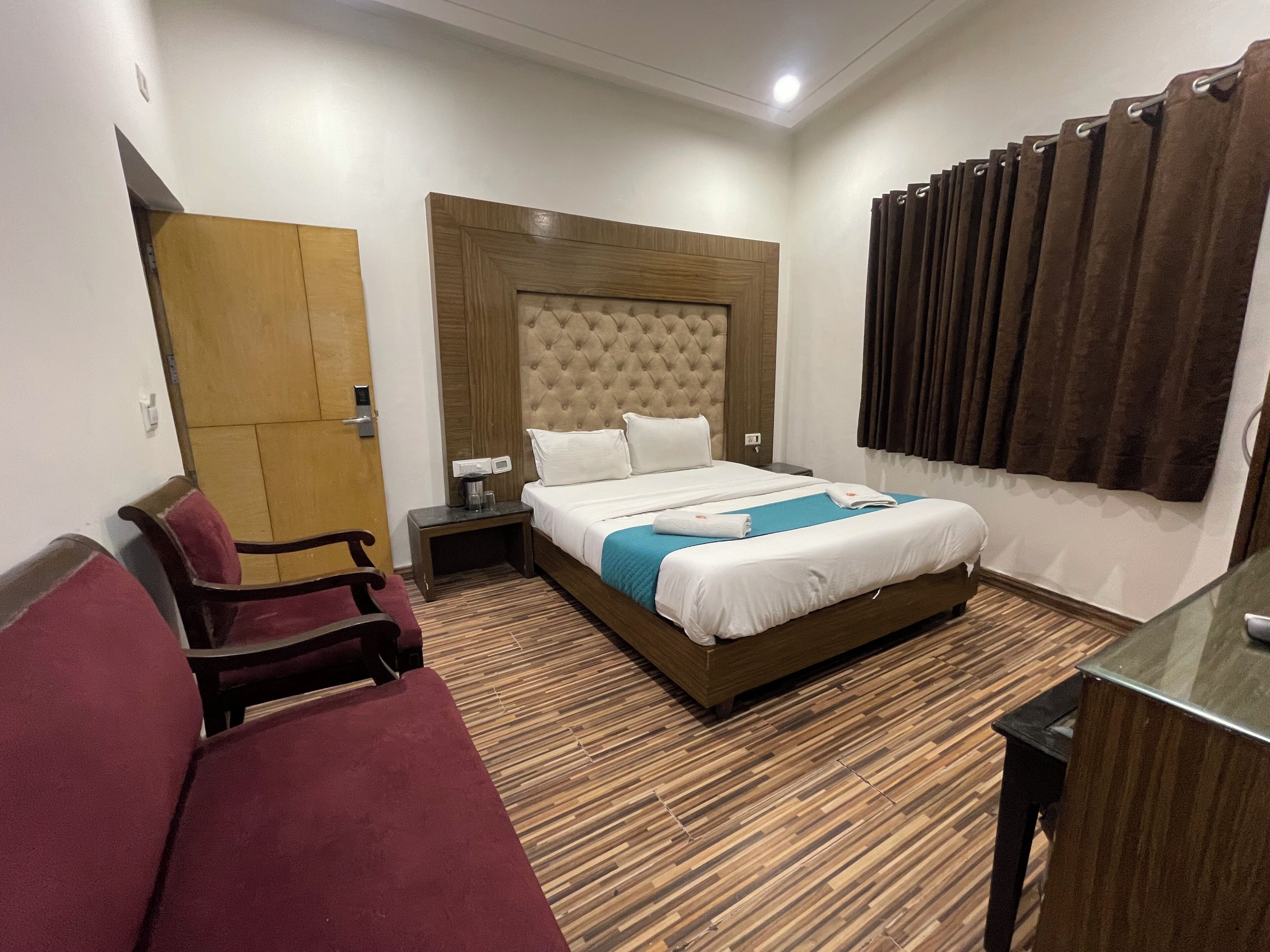 Quarto de hotel com uma cama grande, uma escrivaninha, uma cadeira e um guarda-roupa.