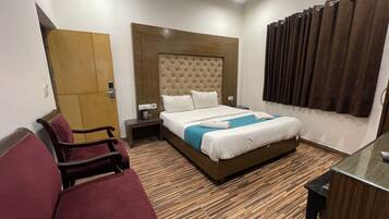 Quarto de hotel com uma cama grande, uma escrivaninha, uma cadeira e um guarda-roupa.