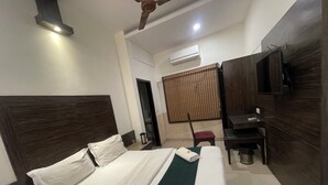 A hotel room with a bed, a desk, a chair, a TV, and an air conditioning unit. - The Mohan By LIVIQ Delhi Railway Station (New Delhi)