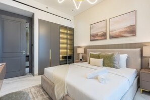 A modern bedroom with a large bed, bedside tables, a wardrobe, and two wall-mounted paintings. - Just a Stone Throw from the Public Park and a Short Drive from Butterfly Garden (Dubai)