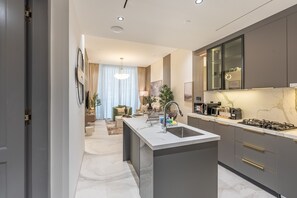 Et moderne køkken med en central ø, indbyggede apparater og et stort vindue.