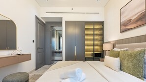 A modern hotel room with a large bed, a bedside table, a mirror, a wardrobe, and a bathroom visible through an open door. - Just a Stone Throw from the Public Park and a Short Drive from Butterfly Garden (Dubai)