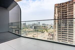A balcony with a city view, a glass railing, and a partially constructed building. - Just a Stone Throw from the Public Park and a Short Drive from Butterfly Garden (Dubai)