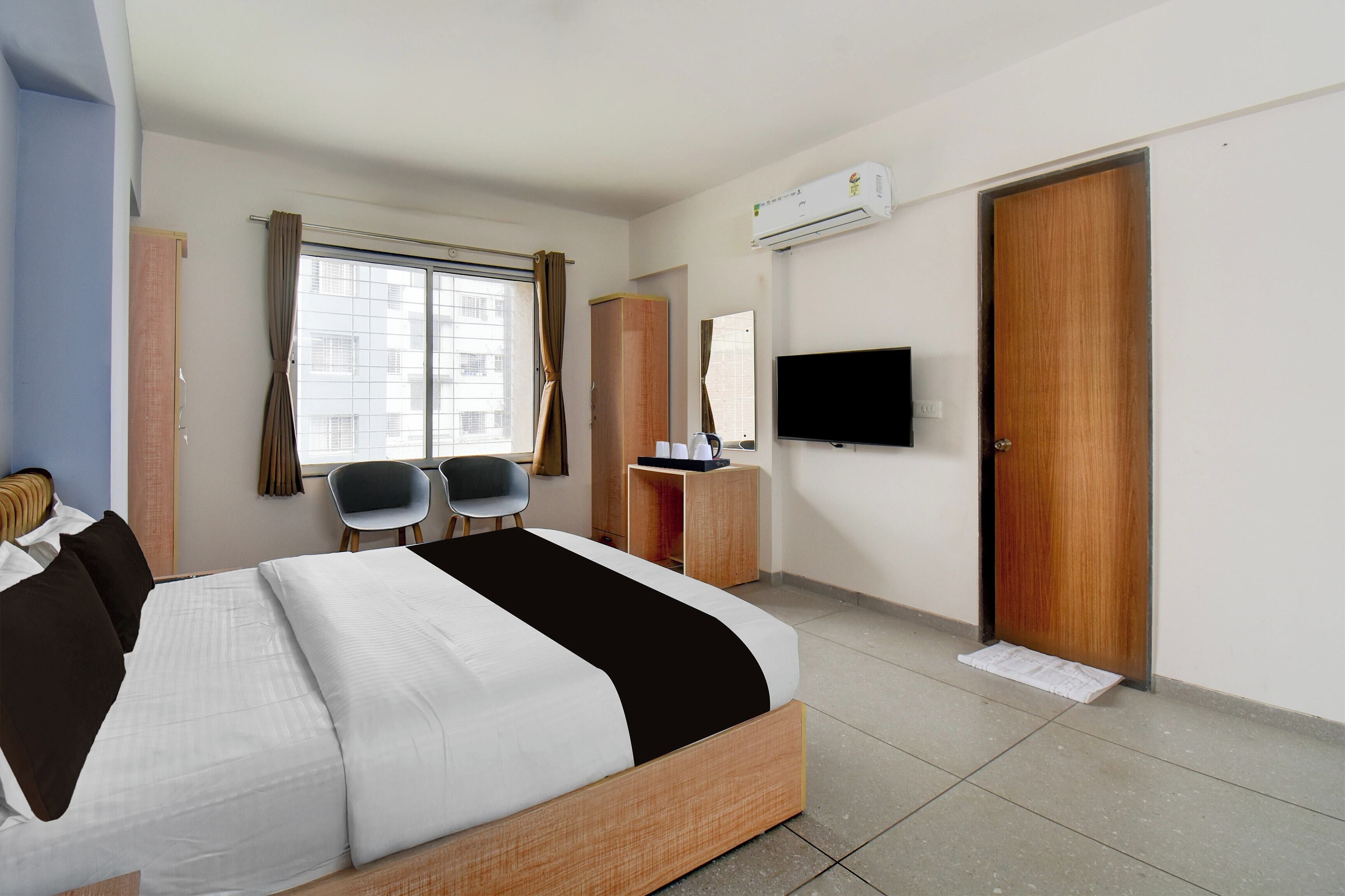 Habitación de hotel con una cama, dos sillas, un escritorio con televisor de pantalla plana y un armario.