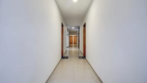 Un lungo e stretto corridoio d'hotel con porte su entrambi i lati, che conduce alle camere.