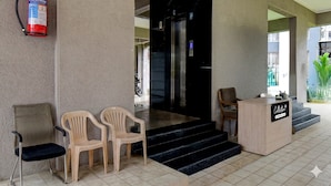 Un'area reception con un estintore montato alla parete, una scrivania reception e una scala che conduce a un ascensore.