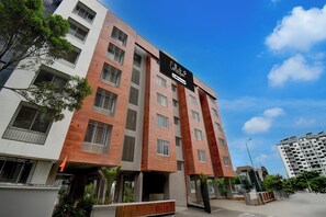 A multi-story building with a mix of brick and white facade, large windows, and a prominent sign indicating it is serviced by OYO. - Super Collection O Katraj Bus Stop (Pune)