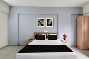 A hotel room with a bed, two nightstands, a wardrobe, and two framed leaf art pieces on the wall. - Super Collection O Katraj Bus Stop (Pune)