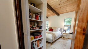 Une chambre à coucher avec un lit, une table de chevet et une bibliothèque remplie de livres et de jeux de société.