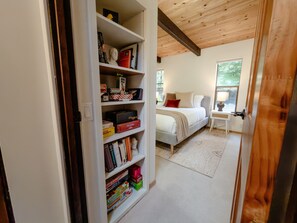 Ein Schlafzimmer mit einem Bett, einem Nachttisch und einem Bücherregal voller Bücher und Gesellschaftsspiele.