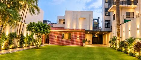 A residential building with a well-maintained lawn, a tiled exterior wall, and a balcony with railing.