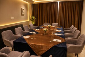 A conference room with a long table, chairs, and a plant. - HOTEL GARDENIA INN (Gwalior)