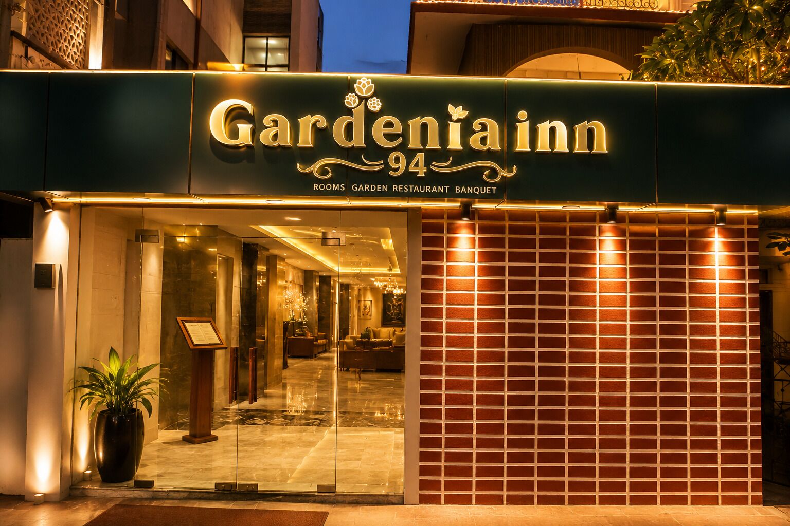 The exterior of a hotel named 'Gardenia Inn' with a sign indicating it offers rooms, a garden restaurant, and a banquet.