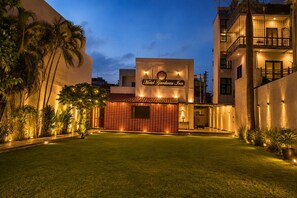 A hotel named 'Hotel Gardenia Inn' with a well-lit entrance, a tiled facade, and a lawn in front. - HOTEL GARDENIA INN (Gwalior)