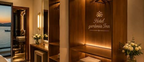 A hotel room with a view of the water, a mirror, a vanity with a sink, a robe, and a sign reading 'Hotel gardenia Inn'.