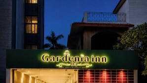 Entrada de un hotel con un letrero que dice 'Gardenia Inn 94' y un corredor cubierto.