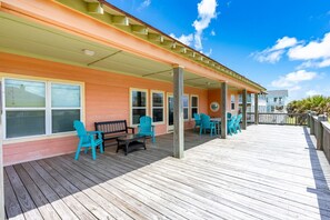 A covered outdoor deck with wooden flooring, turquoise chairs, and a bench. - Beachy Keen- 2nd Row w/ great Views, Pool Table! 3 Bedroom, 3 Bath- Sleeps 10 (Crystal Beach)