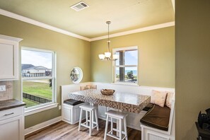 A kitchen with a built-in island, bar stools, and a view of the outside. - Beachy Keen- 2nd Row w/ great Views, Pool Table! 3 Bedroom, 3 Bath- Sleeps 10 (Crystal Beach)