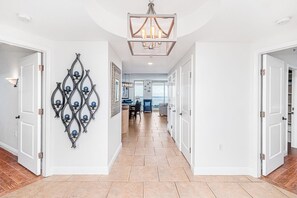 Un couloir agrémenté d’un lustre, d’un élément décoratif mural et donnant sur une salle à manger.