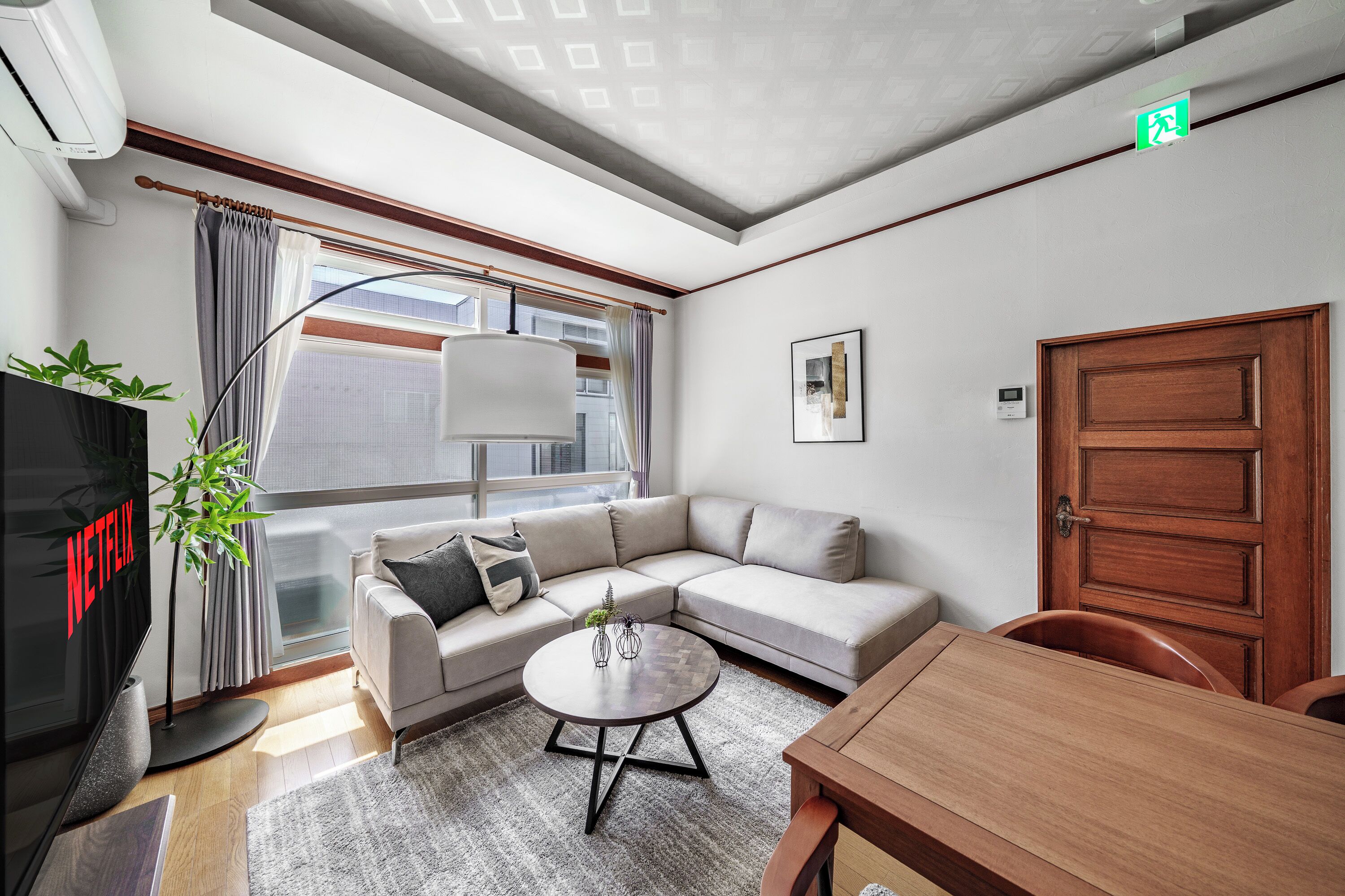 Una sala de estar moderna con un sofá, una mesa de centro, un televisor y una puerta de madera.