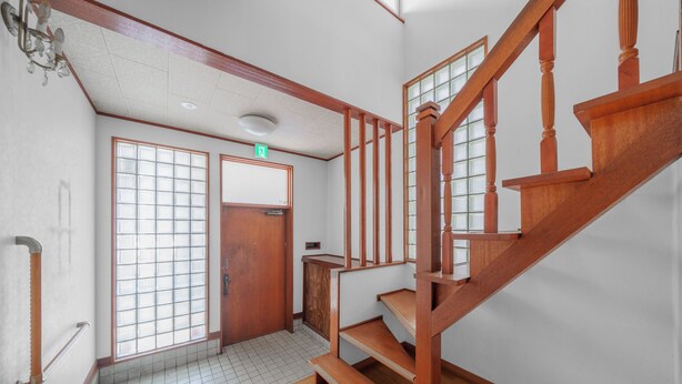 Una escalera de madera con barandilla y una puerta con ventanal.