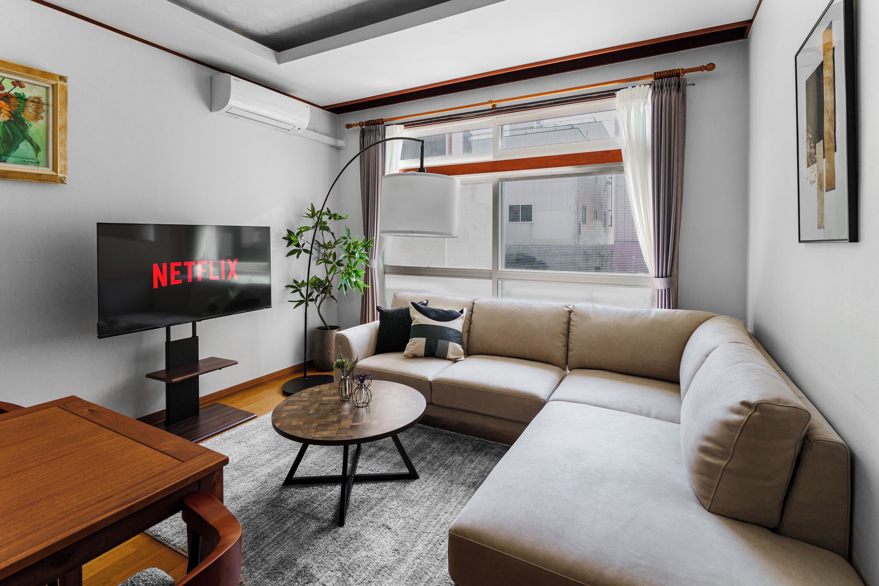 Una sala de estar moderna con un televisor de pantalla plana, un sofá, una mesa de centro y una planta en maceta.