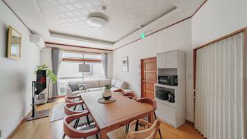 A modern living room with a dining area, a sofa, a coffee table, and a TV.