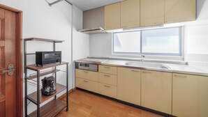 Una cocina moderna con armarios de madera, horno empotrado, cafetera y ventana que proporciona luz natural.