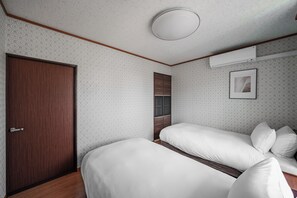 A bedroom with a wooden door, a bed with white bedding, a wardrobe, and a framed picture on the wall. - HARMONY OTARU (Otaru)