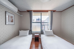 A hotel room with two single beds, a small table, a window with curtains, patterned wallpaper, and a ceiling light fixture. - HARMONY OTARU (Otaru)