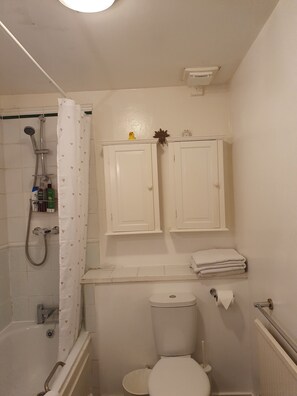 Ein Badezimmer mit Dusche, Toilette und zwei Schränken über dem Waschbecken.