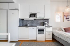 A compact kitchenette with a Bosch refrigerator, microwave, coffee maker, and a stove.