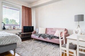 Quarto moderno com sofá, TV, escrivaninha e cadeira.