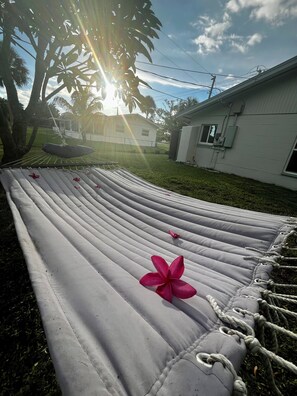 A hammock tied between trees in a backyard with a house in the background. - Charming 3-bedroom house in Fort Myers hot tub, fully fenced, close to Sanibel (Fort Myers)