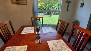 Una mesa de comedor con acabado de madera, rodeada de sillas y una lámpara decorativa colgante.