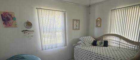 A bedroom with a bed, a ceiling fan, a bean bag, and a rug.