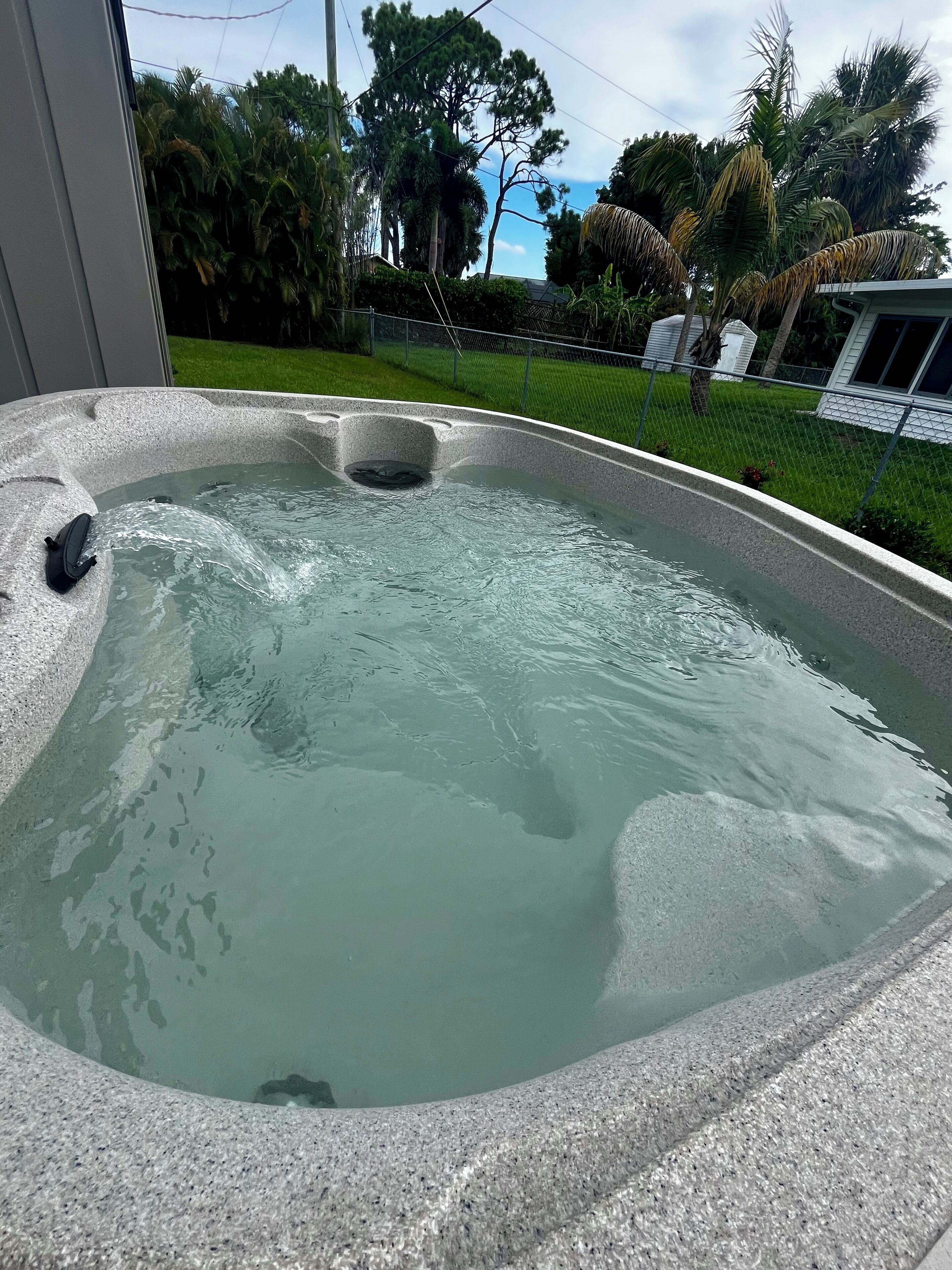 A hot tub with a clear view of the surrounding garden and trees.