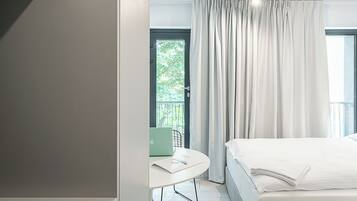 Habitación de hotel moderna con una cama, un escritorio con una computadora portátil y vistas a zonas verdes.
