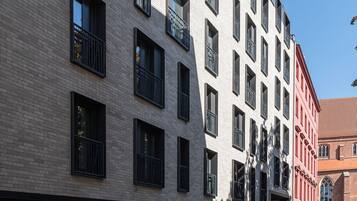 A multi-story building with a modern architectural design, featuring balconies and large windows.