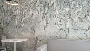 A modern interior with a marble-patterned wall, a round white table, and a grey sofa. - RentPlanet - Jodłowa Residence (Wrocław)