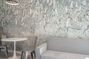 A modern interior with a marble-patterned wall, a round white table, and a grey sofa. - RentPlanet - Jodłowa Residence (Wrocław)
