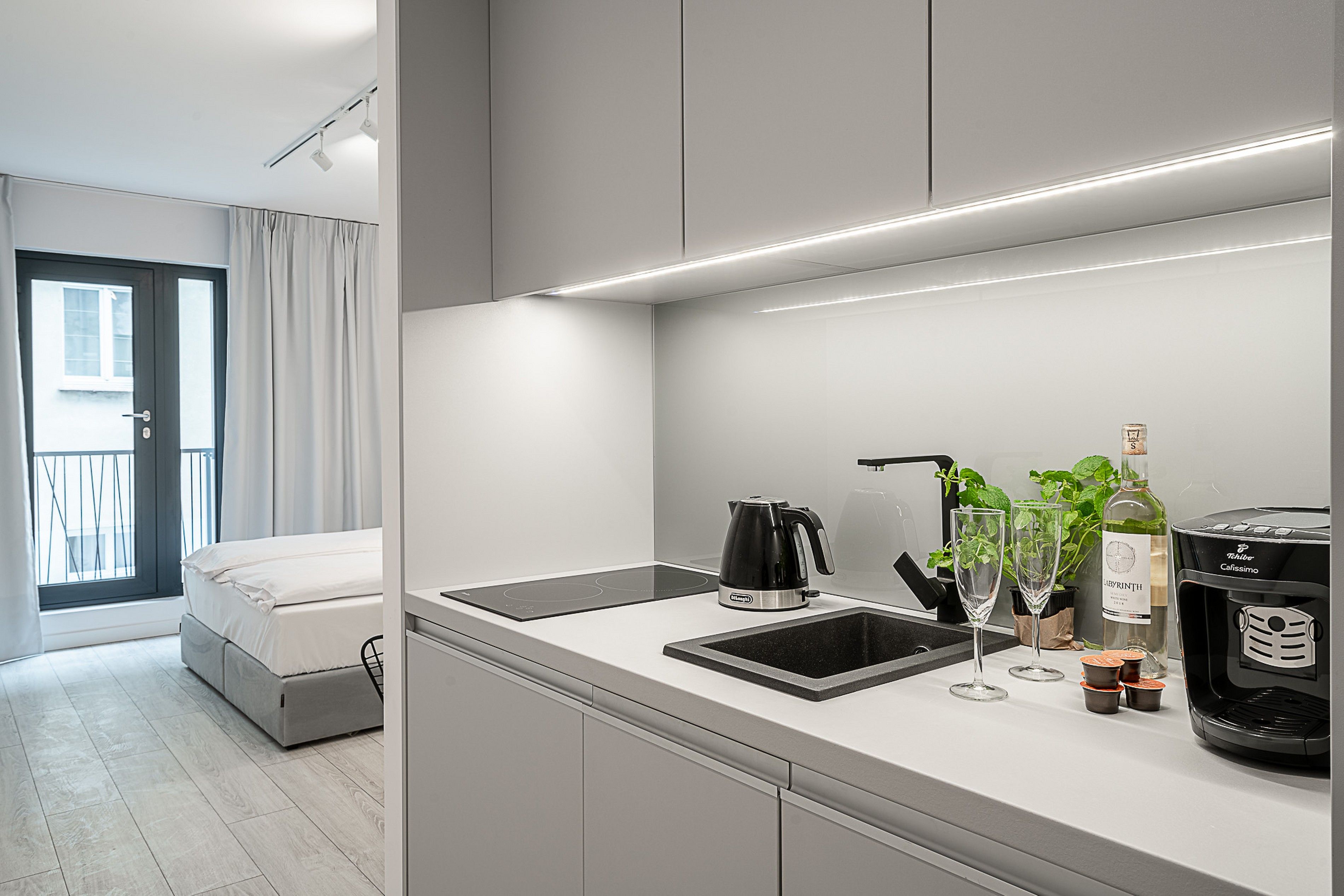 Una cocina moderna con estufa integrada, cafetera y una copa de vino.